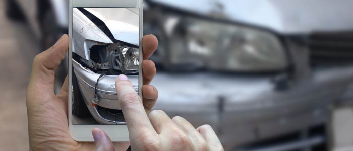 Man taking picture of his damaged car.