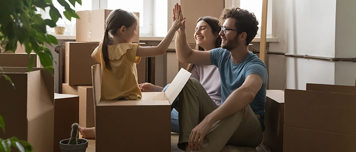 Amid the chaos of moving, a child and an adult pause to share a joyful high-five.